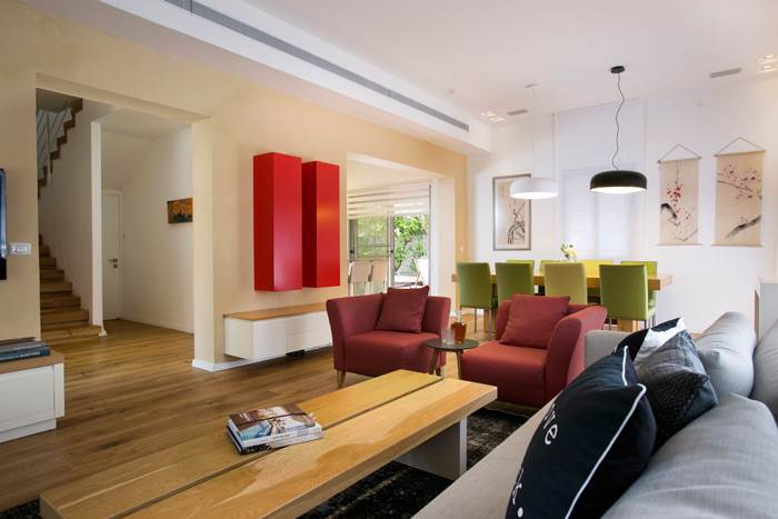 הסלון עוצב במראה חמים עם משחקי צבעוניות על גווני אדום, ירוק ומנעדים של אפור