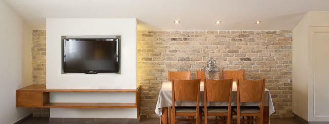סלון ופינת אוכל הכוללים קיר טלוויזיה בשילוב שידת עץ. Niego Design