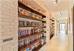 ספריה הבנויה בתוך קירות בריקים שיוצרים אווירה חמימה ומזמינה. עיצוב: מעשה בבית