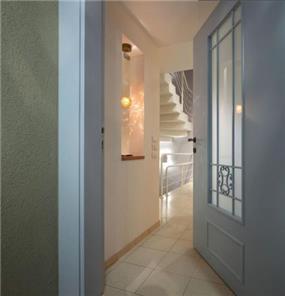 מבט לכניסה לבית בדגש על תאורת מבואה מיוחדת בגומחת גבס בעיצוב ותכנון של נגה ארנסון