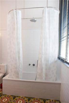 חדר אמבטיה ביחידת הורים עם וילון תלוי מהתקרה בעיצוב ותכנון של הילה לוסקי