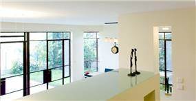 מבט מקיף אל פנים הבית. חלל בהיר עם דלתות יציאה לחצר עם פרזול כהה ודומיננטי. עיצוב: Saab Architects