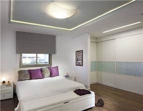 חדר שינה הצמוד לחדר ארונות, המשלב תאורת תקרה, נגרות ופרטי סטיילינג. עיצוב: יוסי שאול YS-DESIGN