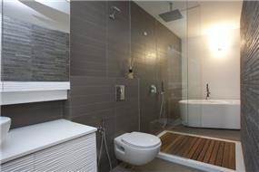 חדר רחצה שכולל אמבטיה ומקלחון צמודים. עיצוב של ענבל ברקוביץ
