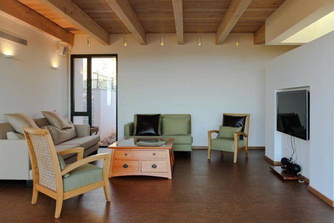 קורות עץ חשופים בתקרה, פרטי ריהוט מעניינים ועיצוב מינימלי בסלון. saab architects 