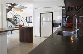 מבט מהמטבח לעבר החלל הציבורי בבית והמדרגות. עיצוב של saab architects 