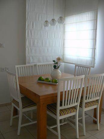 שילוב של שולחן אוכל מעץ אלון עם כסאות לבנים ווילון.עיצוב של רויטל רודצקי